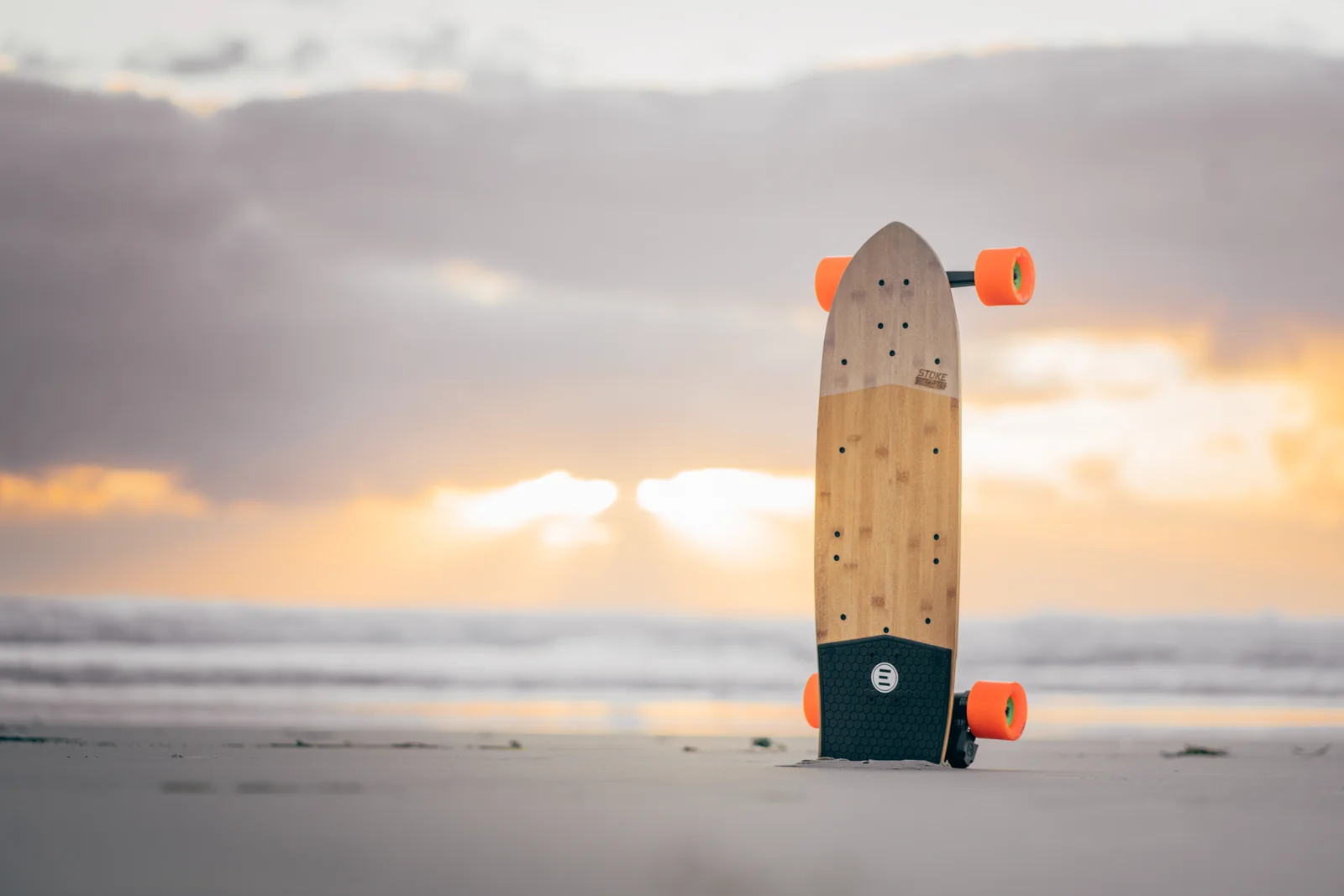 Stoke X o Fusion - skate eléctrico Evolve apoyado cerca del océano